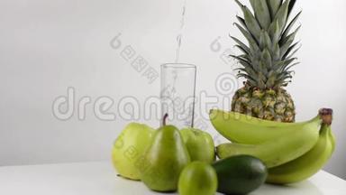 绿色成分由香蕉、苹果、菠萝和梨组成。 高的玻璃杯里装满了水。